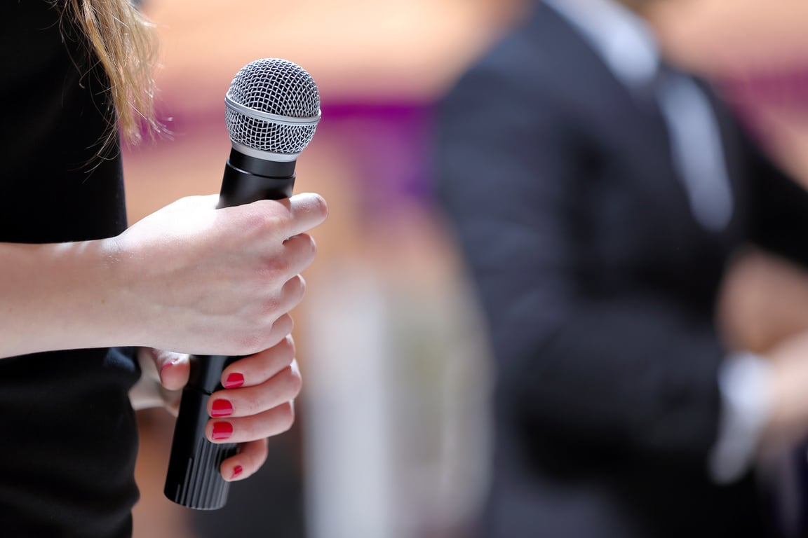 Woman stands on stage with microphone durring speech